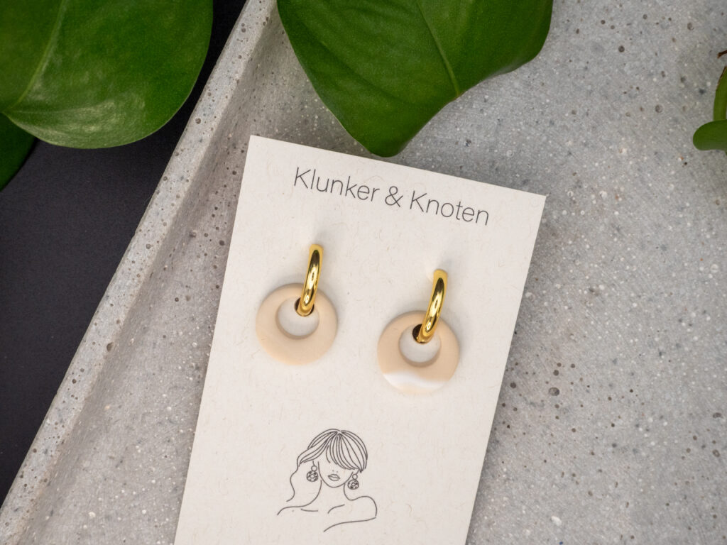 Goldfarbene Creolen aus Edelstahl mit einem beigen, runden Wechselanhänger