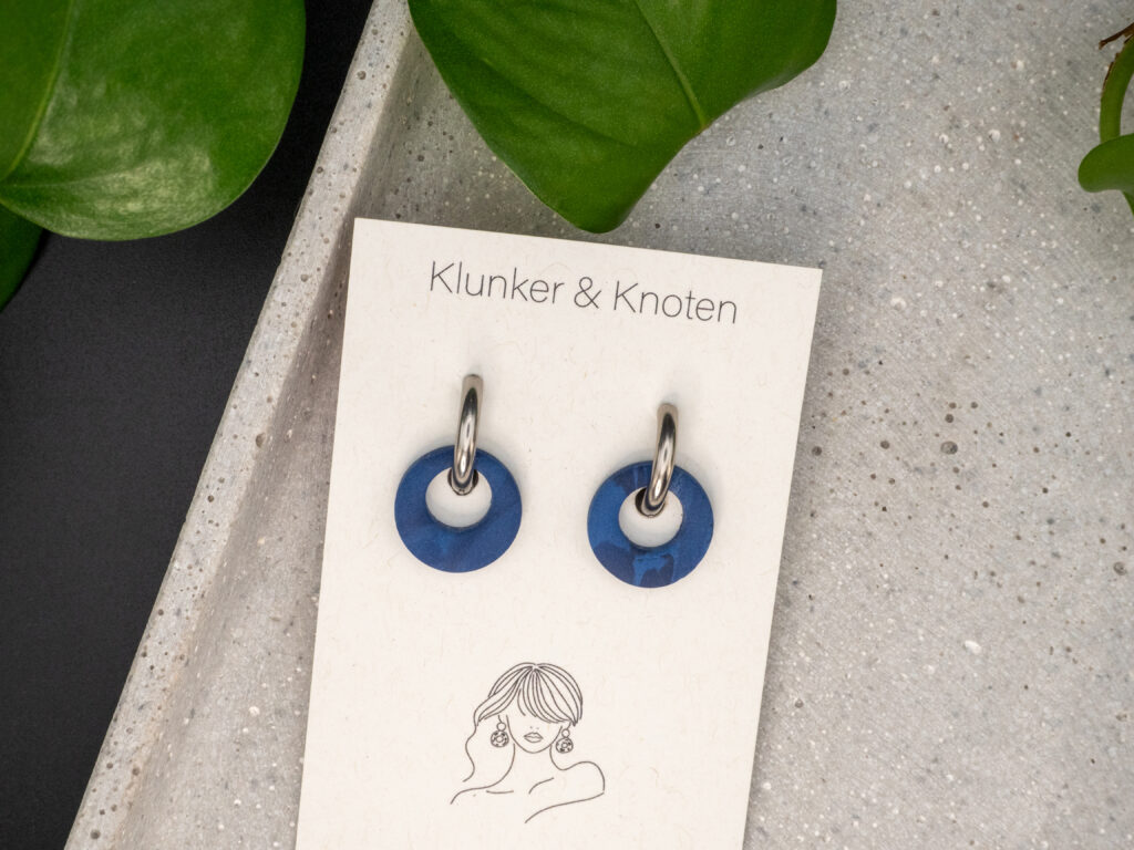 Silberfarbene Creolen aus Edelstahl mit einem runden Anhänger in Blau