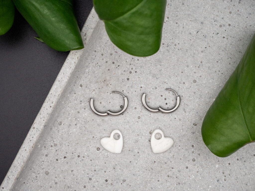 Silberfarbene Creolen aus Edelstahl mit Herzanhängern in Perlmutt und Weiß