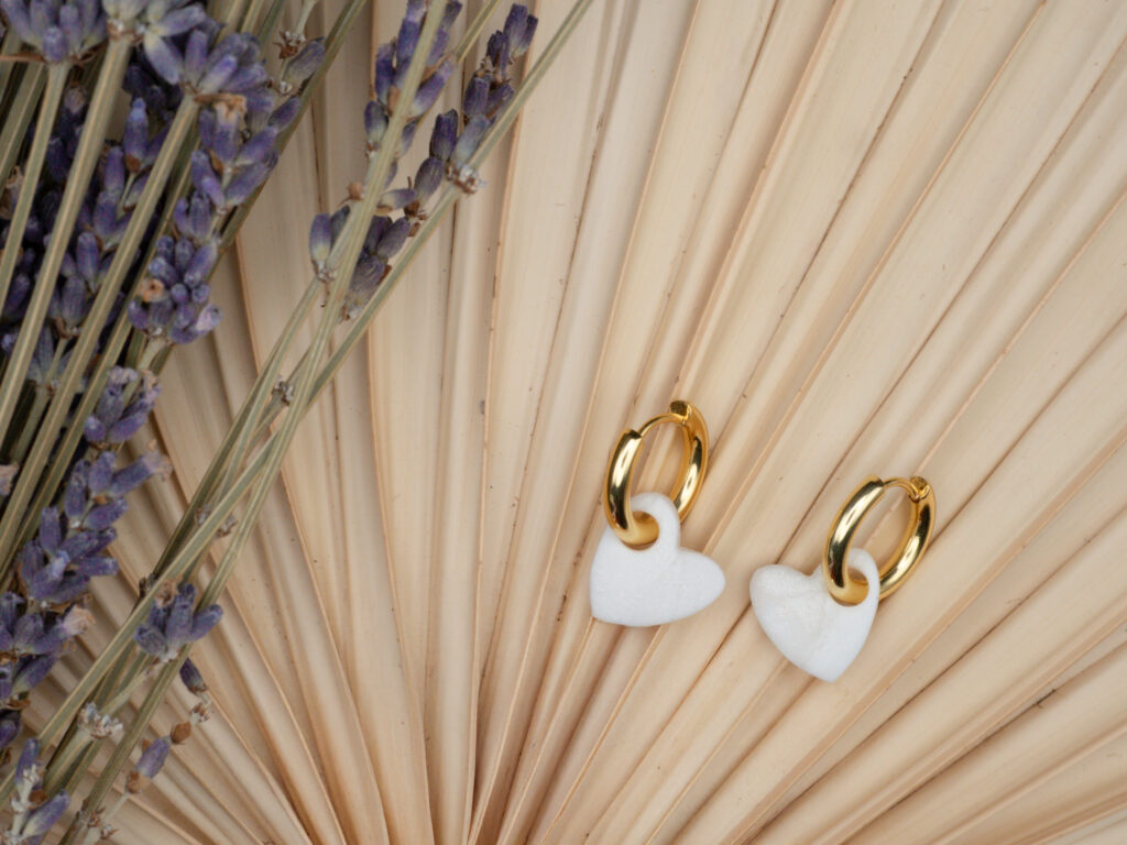 Goldfarbene Creolen mit Herzanhängern in Perlmutt und Weiß