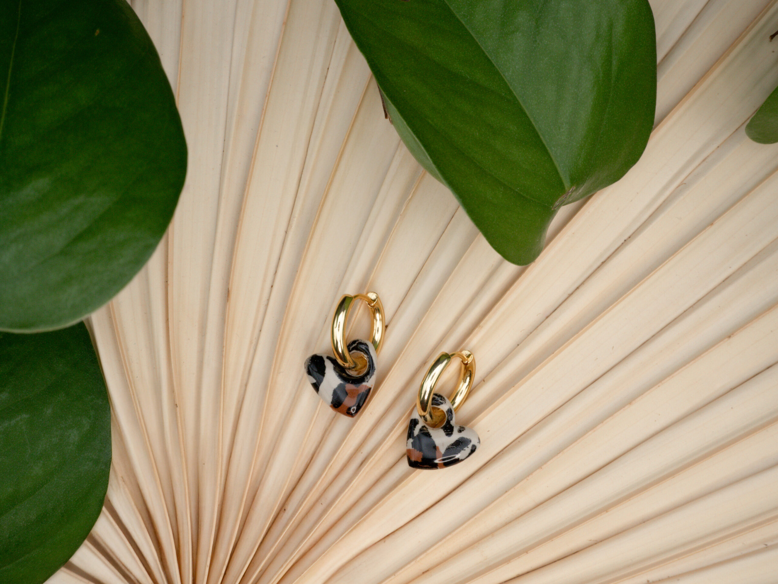 Bild von goldfarbenen Creolen mit Herzanhängern mit Leo-Muster