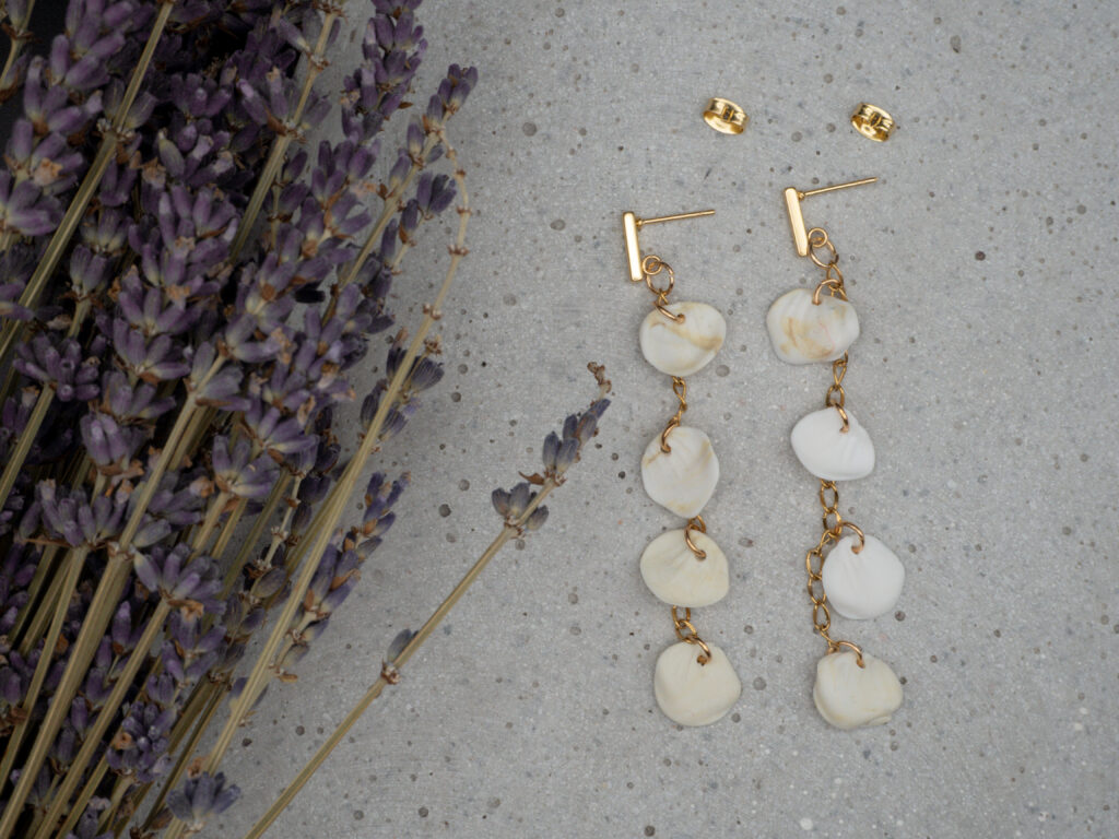 Elegante goldfarbene Hängeohrringe mit einigen modellierten Blütenblättern aus Polymer Clay in Weiß und Beige