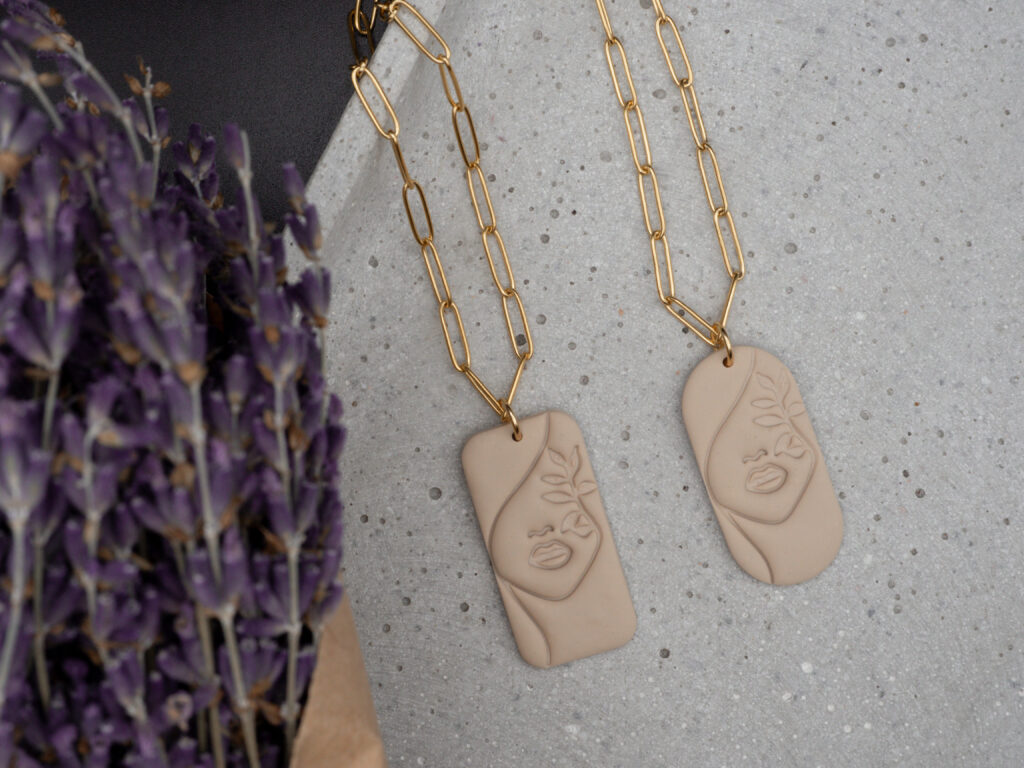 Goldfarbene Ketten aus Edelstahl mit beigefarbenen Ketten mit Line Art Motiv in Form eines weiblichen Gesichts