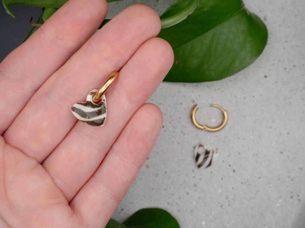 Goldfarbene Creolen mit Herzanhängern im Zebra-Print