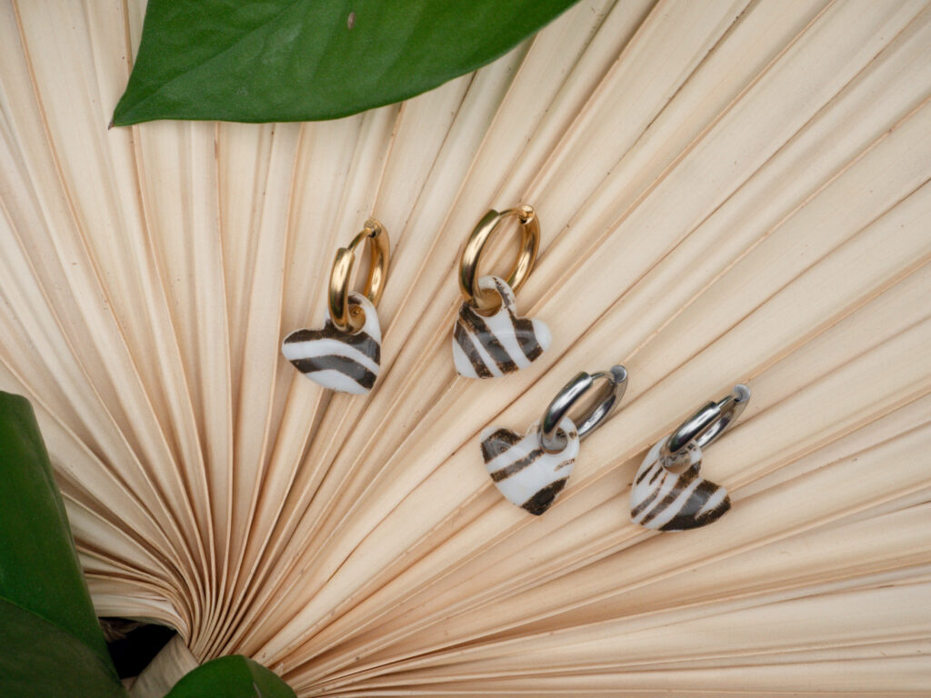 Goldfarbene und Silberfarbene Creolen aus Edelstahl mit Herzanhängern im Zebra-Print