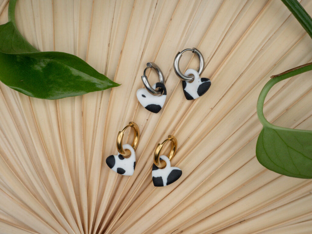 Goldfarbene und Silberfarbene Creolen aus Edelstahl mit Herzanhängern im Kuh-Print